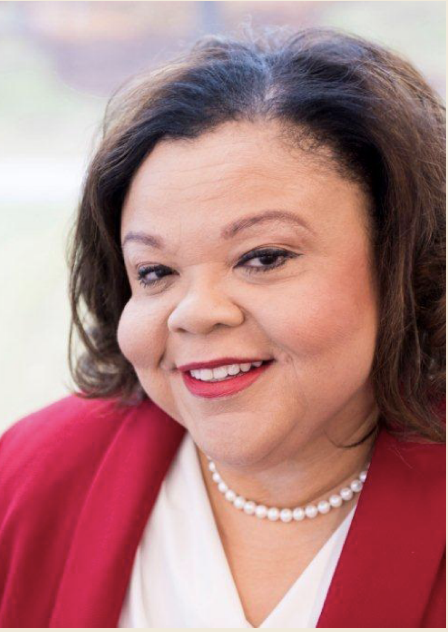 A photo of a women smiling, with a red blazer and white blouse.