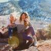 two females sitting on a rock laughing
