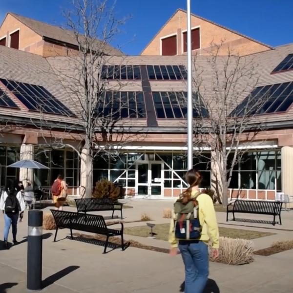 Several people walk toward the large glass doors, windows, and skylights of the SEEC building
