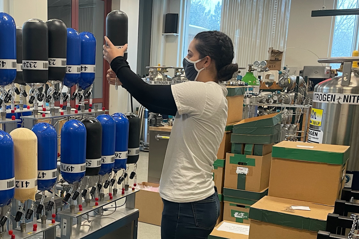 Lab researcher working with a wall of flasks for stable isotope analysis