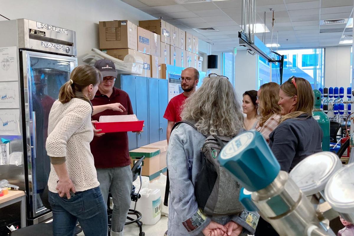 Sylvia Michel explains how analyzing ice cores can tell us about past climatic conditions as Dairy Arts Center curator Drew Austin holds a section of teaching ice.
