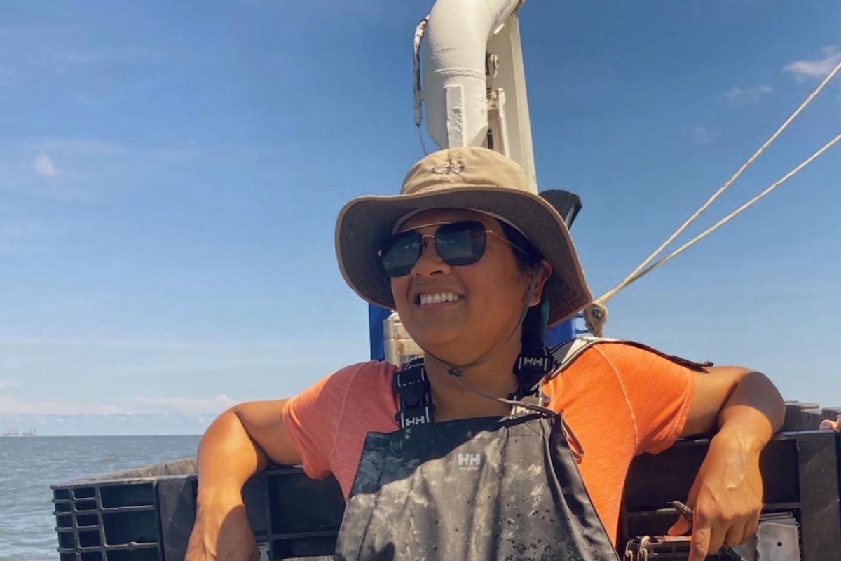 Shaily Rahman works on board a ship in the Gulf of Mexico, wearing a sunhat, sunglasses, and coveralls