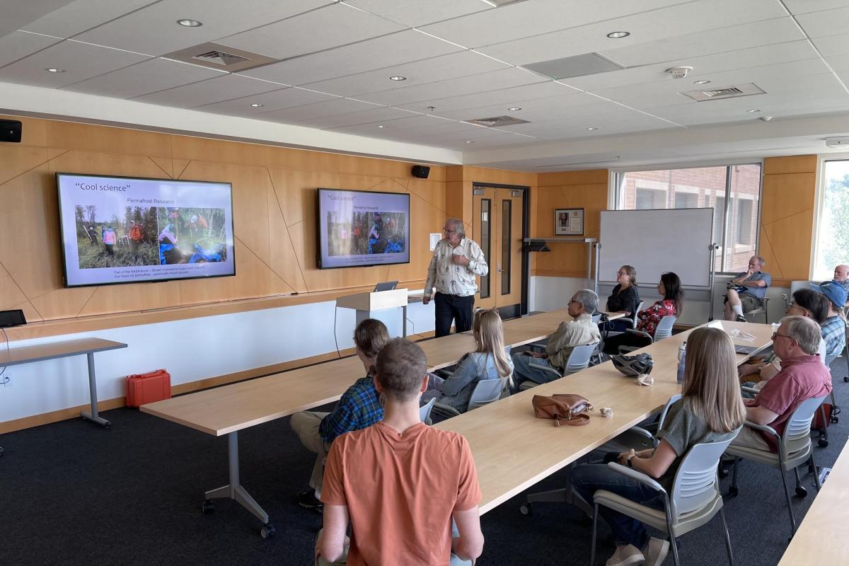 A group of people watch Mark Serreze give a presentation