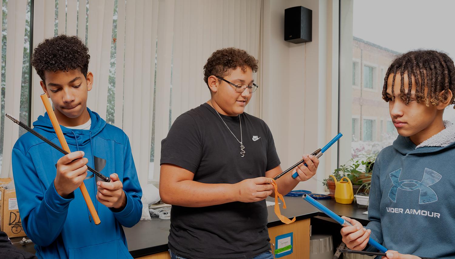 Three young teens hold long metal scientific instruments in a well-lit indoor laboratory. Photo by Gabe Allen, INSTAAR communications specialist.