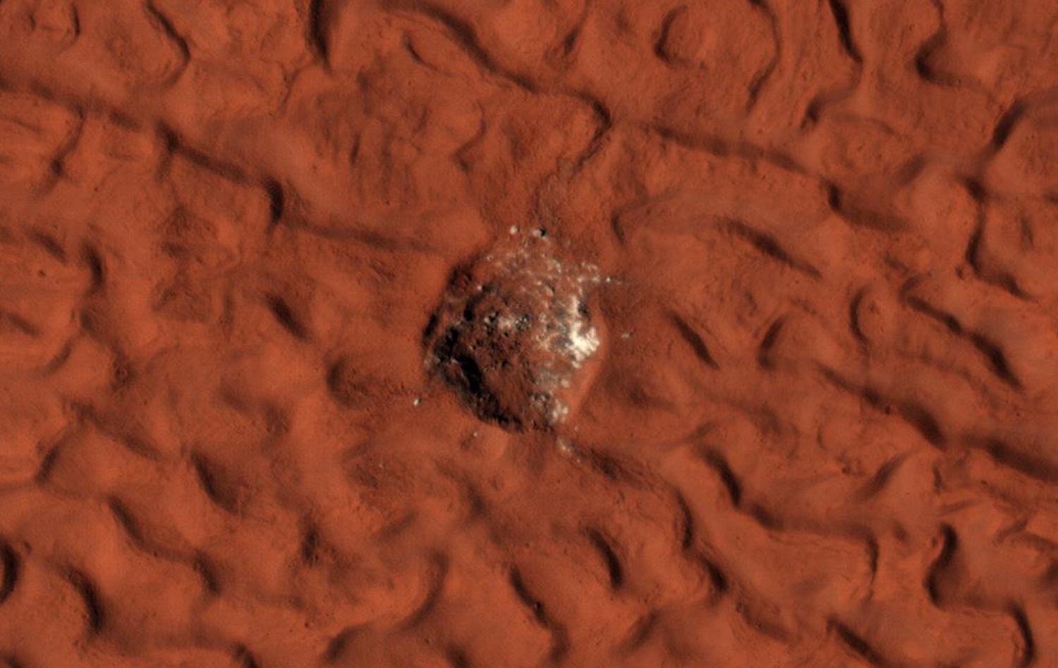 This enhanced-color image shows a 45-meter-diameter crater on the surface of Mars, appearing as a glistening sphere on a rusty red background. Glistening material is interpreted as water ice slowly subliming. Photo credit: NASA/JPL-Caltech/University of Arizona
