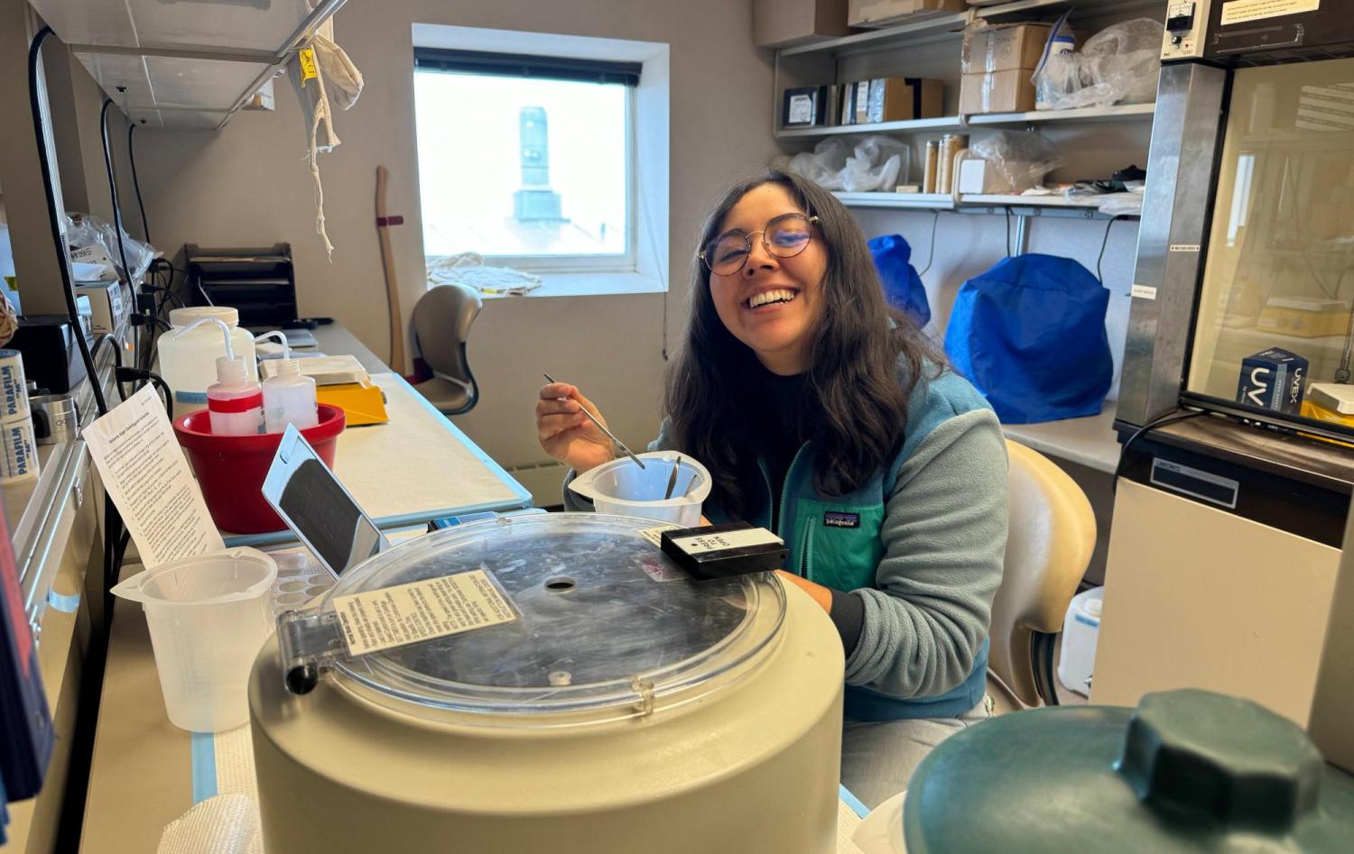 Natalie Aranda sits at a lab bench in Antarctica, surrounded by lab equipment and shelving