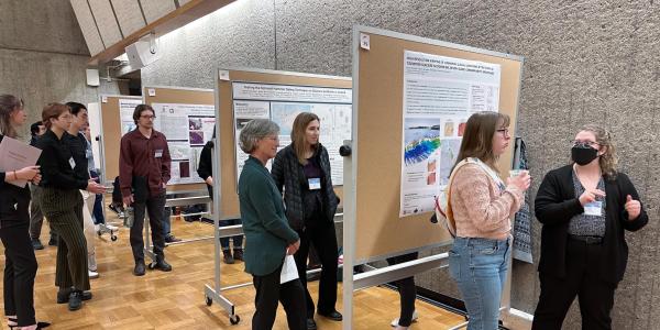 Polar researchers cluster in groups around a series of science posters at the 52nd Arctic Workshop, discussing methods and results.