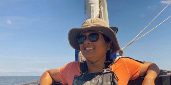 Shaily Rahman works on board a ship in the Gulf of Mexico, wearing a sunhat, sunglasses, and coveralls