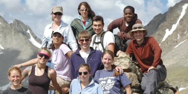 Participants in the Research Experiences for Undergraduates (REU) program at the Mountain Research Station.  They are in a pyramid shaped group, mimicking the mountain peaks on their left and right. 