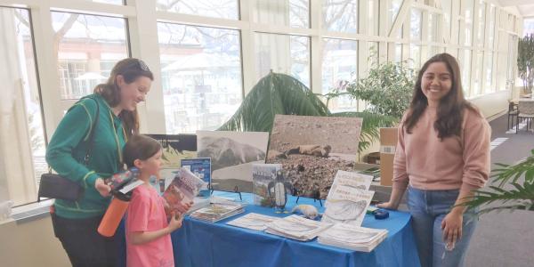 Grad student Natalie Aranda (CU Boulder Engineering) helps give out books to a mother and child at a reading table for the McMurdo Long-Term Ecological Research site in Antarctica.  The event was a family friendly STEAMfest hosted by CU Boulder Science Discovery. 