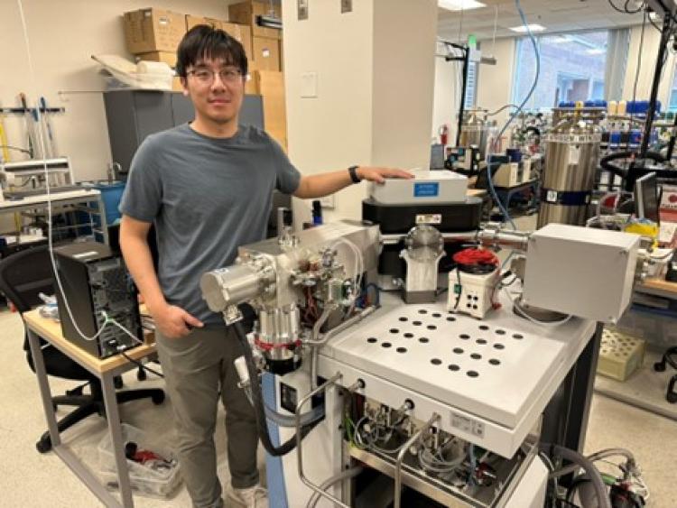 New faculty member Jianghanyang (Ben) Li stands proudy by his new instrument, a Thermo 253+ named Rutherford.
