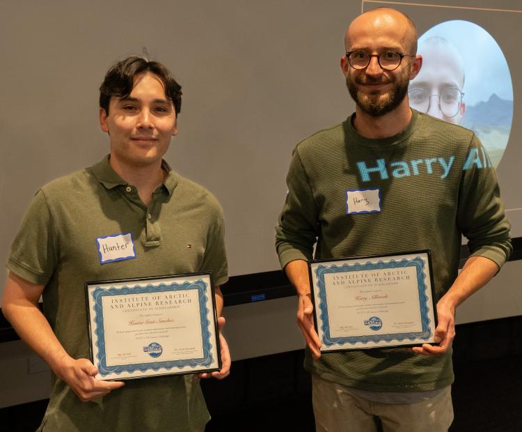 Two young men pose with commemorative plaques