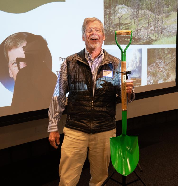 A man poses with a bright green commemorative shovel