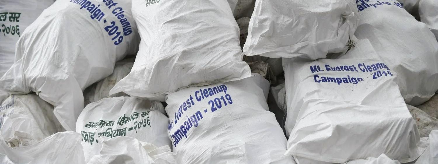 Piles of white trash bags collected from the Everest region, with labels in multiple languages
