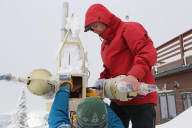 Several researchers work on snow covered meteorological instrumentation at the Storm Peak Lab on top of the Steamboat ski mountain, Colorado.