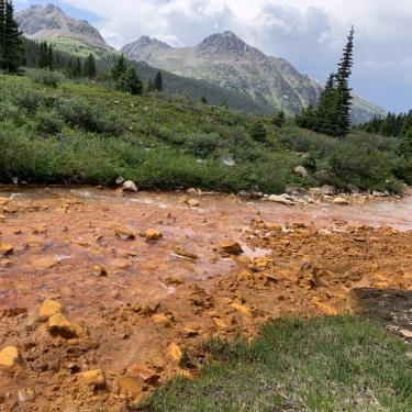 The bed of a subalpine creek in Colorado is orange due to acid rock and mine drainage. Credit: Heather Sackett/Aspen Journalism.