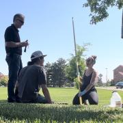 Alli Cook, with campus partners, samples water from a campus storm sewer.