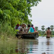 People in a boat and wading in floodwaters