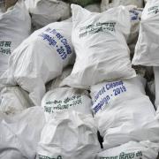 Piles of white trash bags collected from the Everest region, with labels in multiple languages
