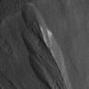 The white material seen within this Martian gully is believed to be dusty water ice. Scientists believe this kind of ice could be an excellent place to look for microbial life on Mars today. This image, showing part of a region called Dao Vallis, was captured by NASA’s Mars Reconnaissance Orbiter in 2009.