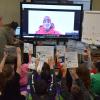 Jared Collins video calls from Antarctica with a group of third graders who are holding up copies of the bilingual book La Foca Perdida/ The Lost Seal, written by Diane McKnight. Credit: William Floyd School District