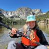 Katie Gannon paddles a small inflatable boat on a high altitude lake in the Rocky Mountains