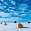 Numerous tents arrayed across the flat white top of the Greenland Ice Sheet. EGRIP ice core camp. Photo: Tyler Jones