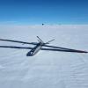 A unmanned aerial aircraft resembling a steel airplane lays atop a vast expanse of ice