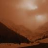 A snow-covered mountain valley is tinged with a dark sepia overtone