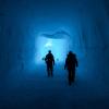 two silhouettes walk away in a tunnel of ice