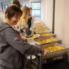 scientists line up to scoop food from hotel trays with smiles on their faces
