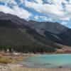 The edge of a turquoise lake below conifer-coated mountains