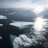 Small chunks of melting ice float in a dark blue sea.