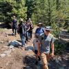 A multidisciplinary team walks through an open forest to survey the future site of an EcoTram, a moving monitoring platform