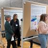 Polar researchers cluster in groups around a series of science posters at the 52nd Arctic Workshop, discussing methods and results.