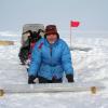 While kneeling in the snow, Bruce Vaughn displays an ice core segment, northeast Greenland