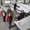 Scientists stand next to airplane used for gathering data on atmospheric emissions and chemicals