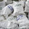 Piles of white trash bags collected from the Everest region, with labels in multiple languages