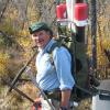 George Aiken in the field, wearing a big backpack for carrying tall tubes.