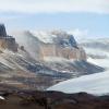 Banded cliffs rise above barren slopes and a large glacier in the dry valleys of Antarctica. The region forms the coldest, driest, and windiest ecosystems known. (Credit: Michael Gooseff/CU Boulder)