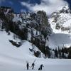 Scientists with skis travel on a snow covered lake with dramatic Teton mountain peaks behind them. 