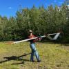 CU Boulder incoming PhD student Paloma Siegel carries an autonomous aircraft (~10 foot wingspan) away from an Alaskan landing strip after a flight