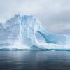 An iceberg, eroded with arches and cracks, floats in the Southern Ocean.