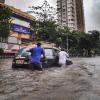 Two people push a car through floodwaters