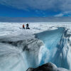 Scientists on the Greeland Ice Sheet next to a meltwater stream (Photo by Jason Gulley)