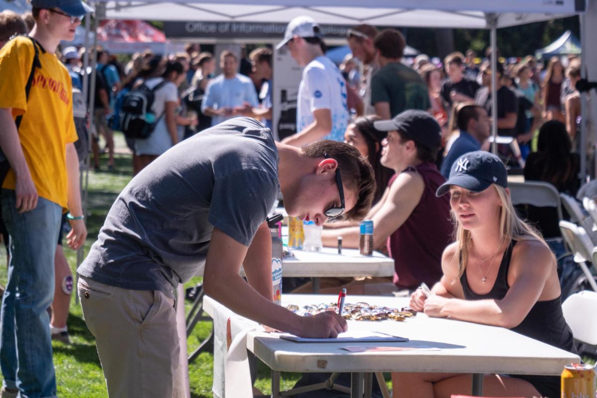 student signing a form at be involved fair