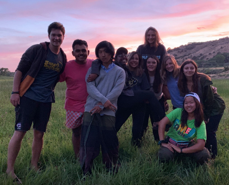 students in a group outside with sunset behind