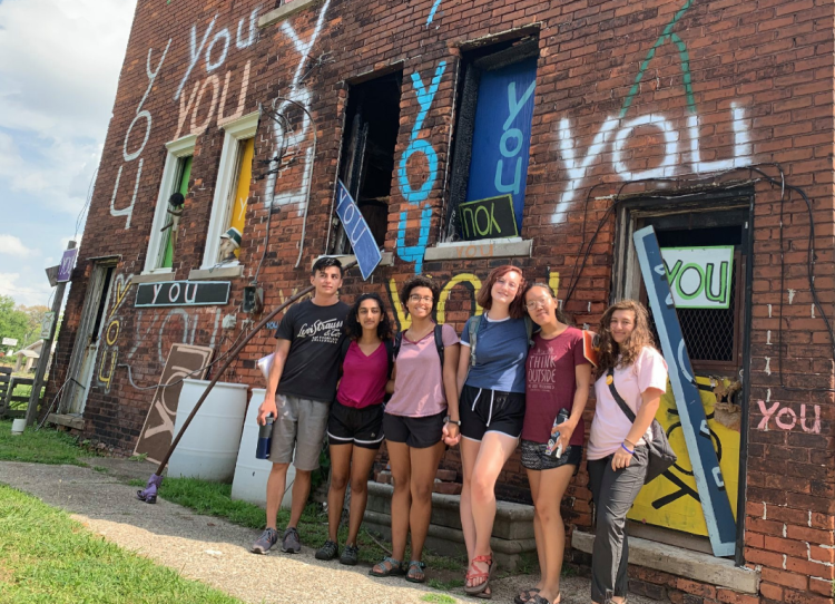 Students in front of brick building in Detroit with the word YOU painted on it