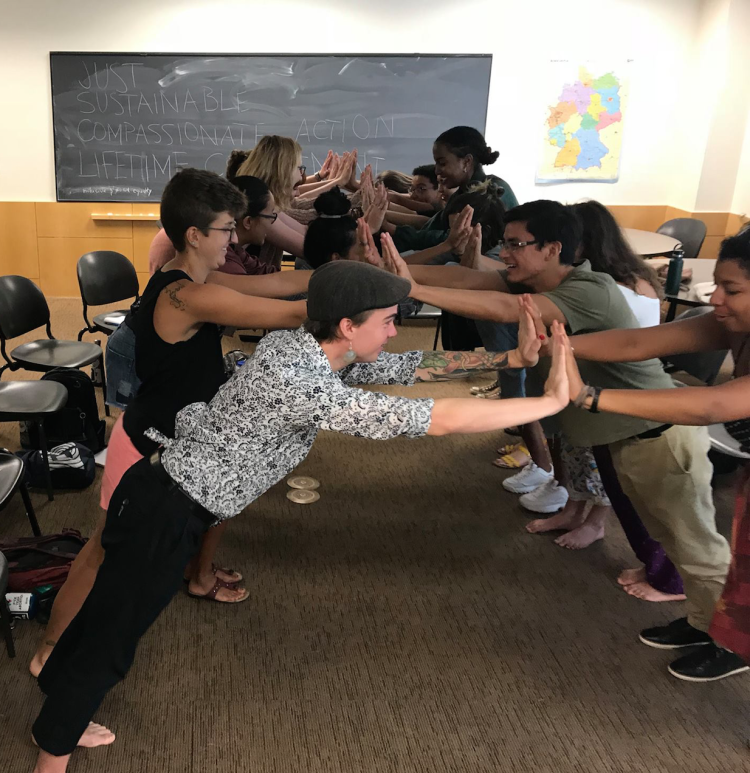 Students participating in a team building activity in 2 lines across from each other with palms pressed against each other