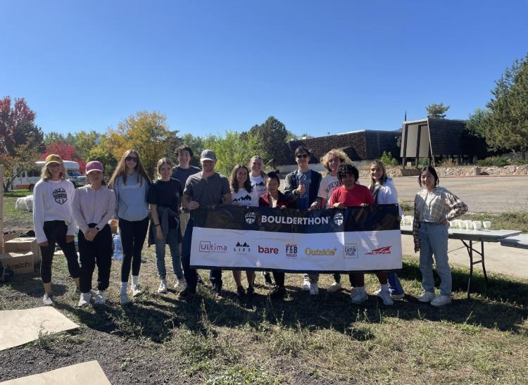 Students holding a sign together in nature
